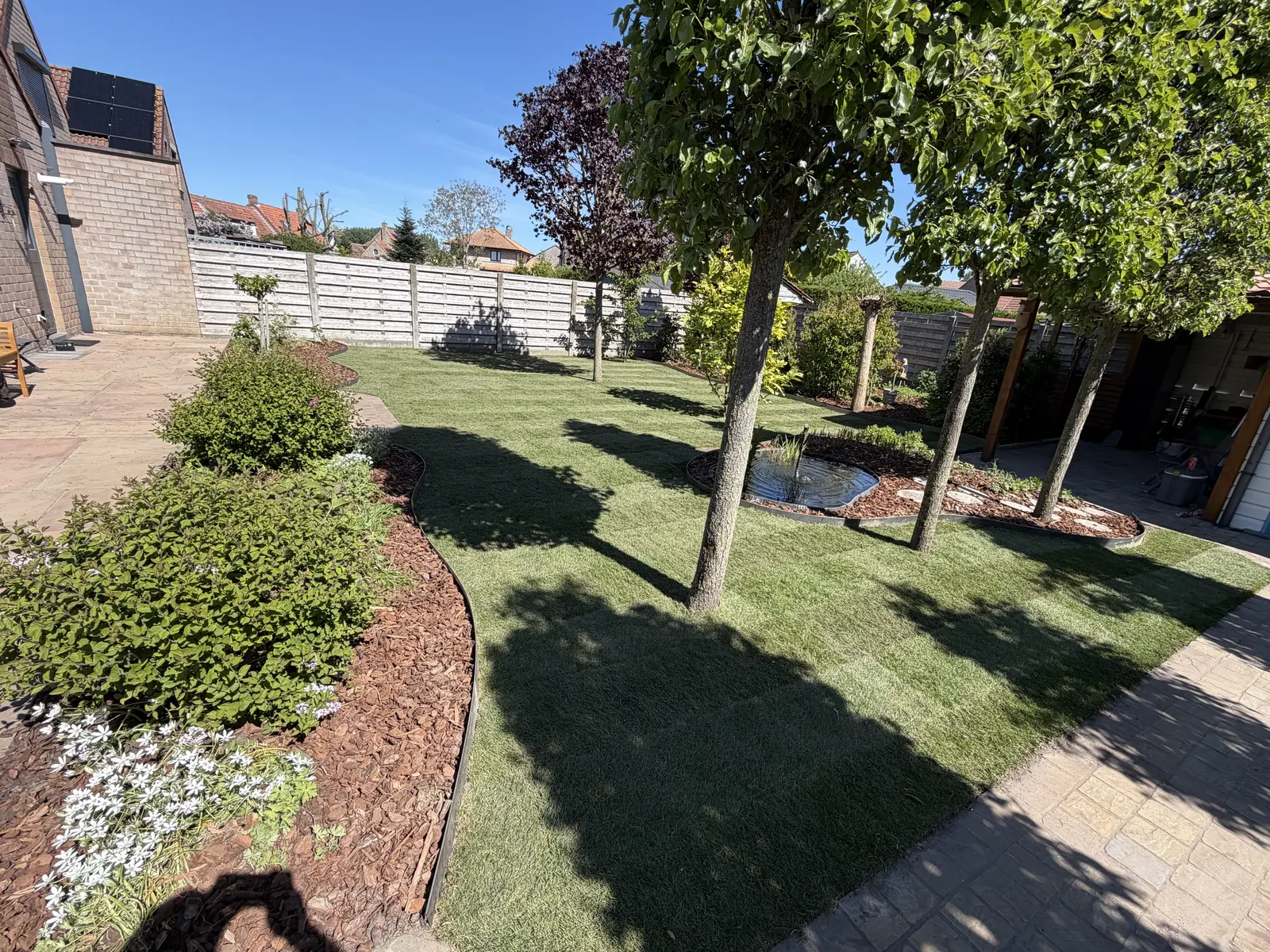 Aangelegde tuin met gazon, borders in schors en een terras