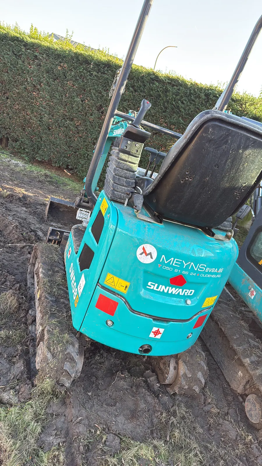 Minigraver die een boomstronk uitgraaft in een tuin