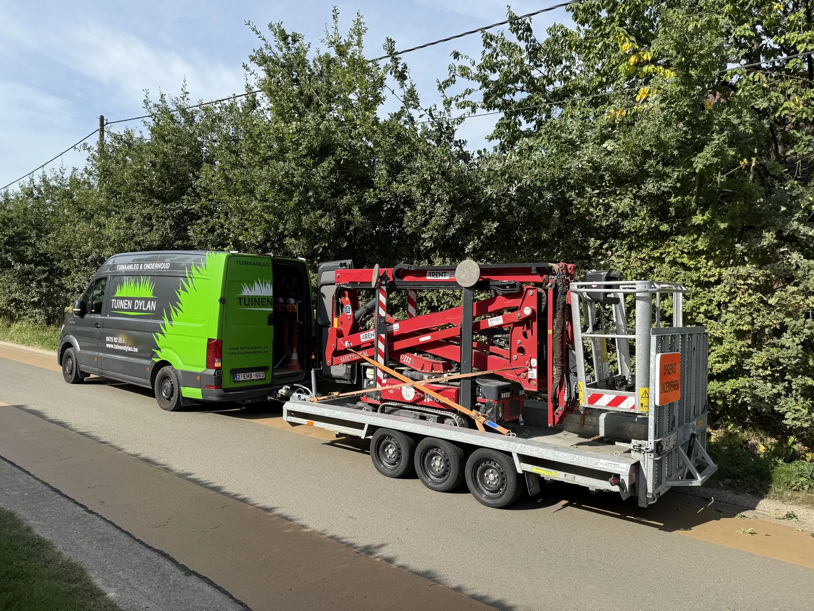 Bestelwagen met hoogtewerker onderweg naar een snoeiwerk