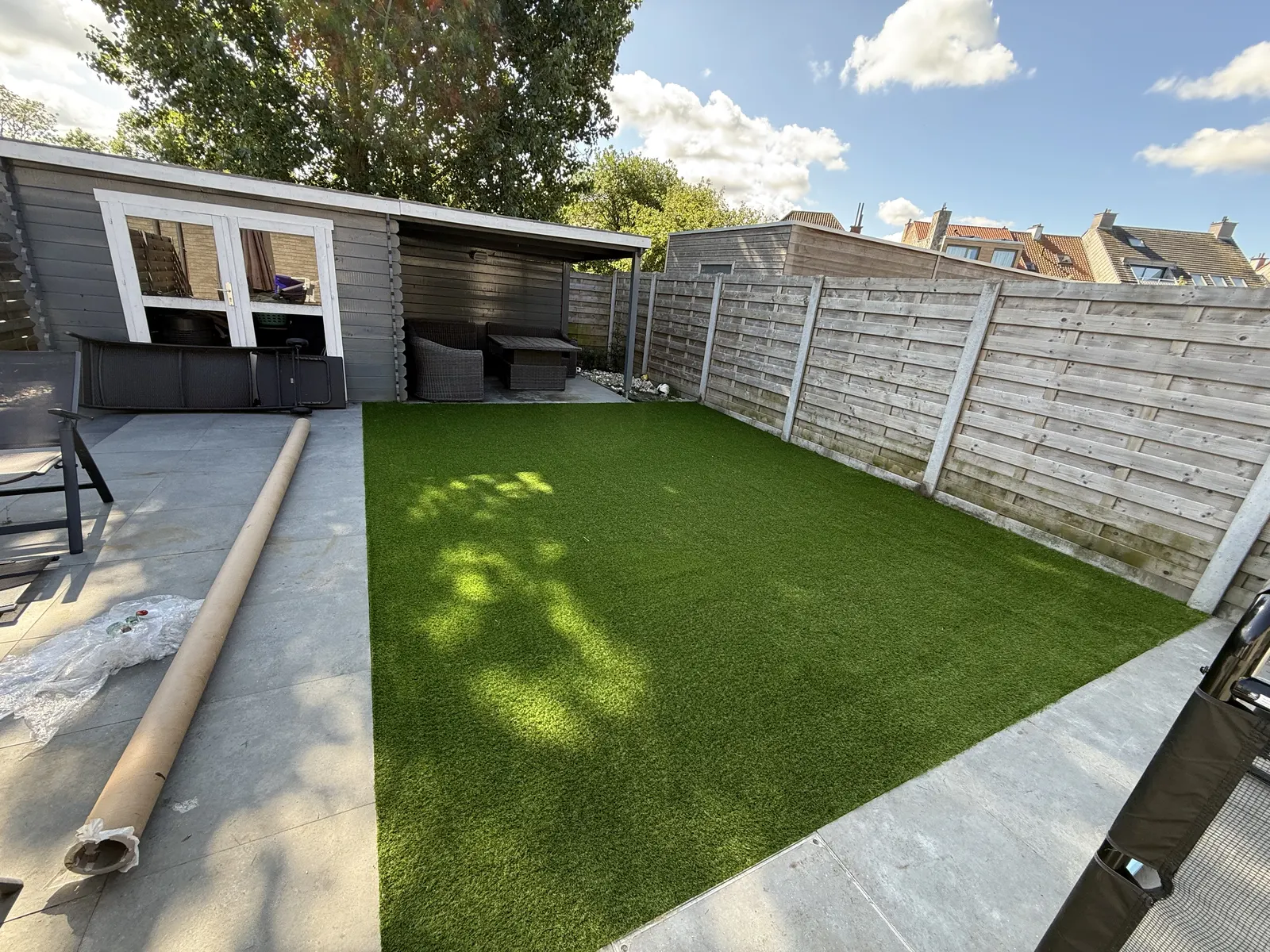Kunstgras aangelegd tussen een terras en een tuinhuis