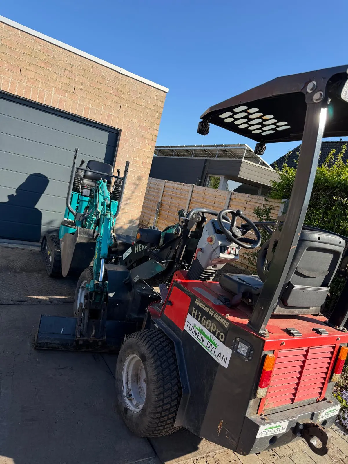 Minigraver en kraanwagen uit het machinepark van Tuinen Dylan