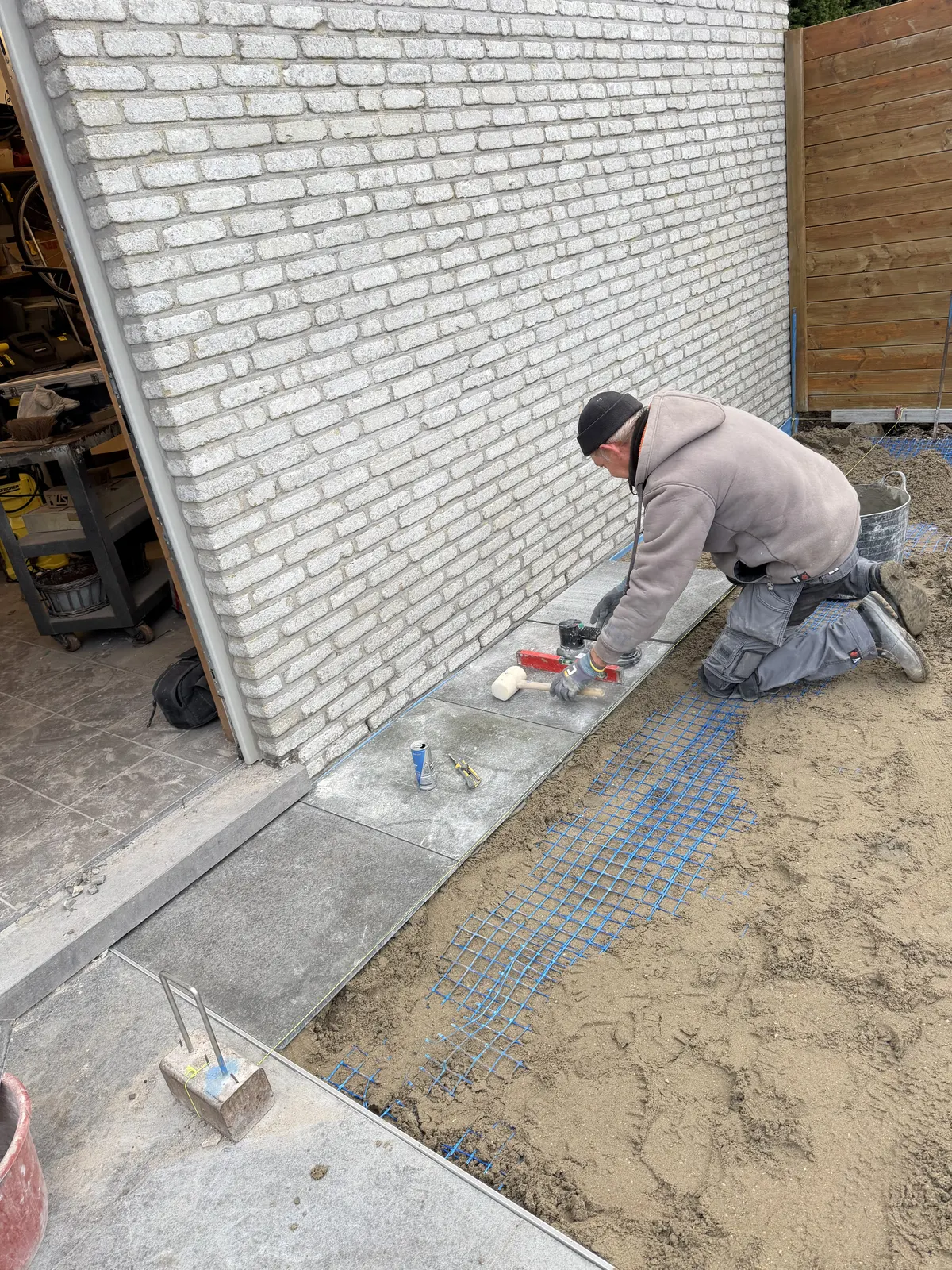Vakman van Tuinen Dylan plaatst terrastegels tijdens de aanleg