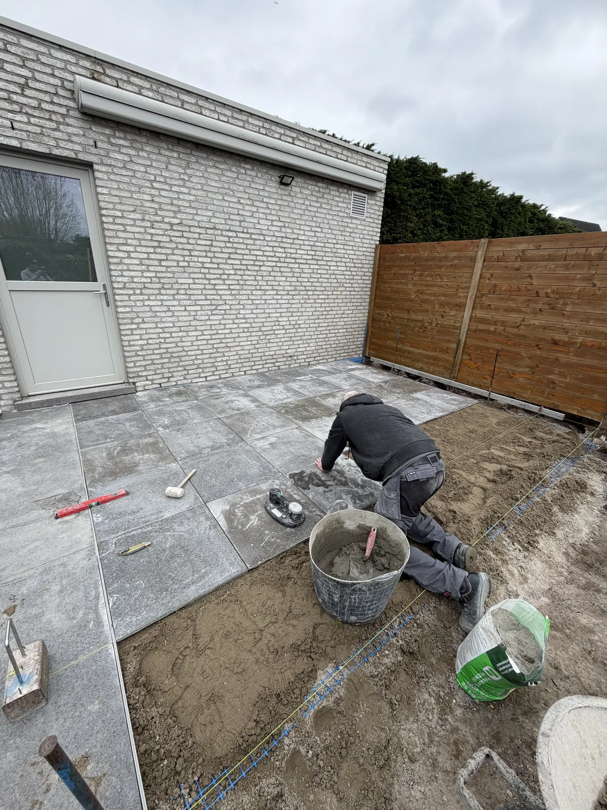 Vakman van Tuinen Dylan legt de tegels van een nieuw terras