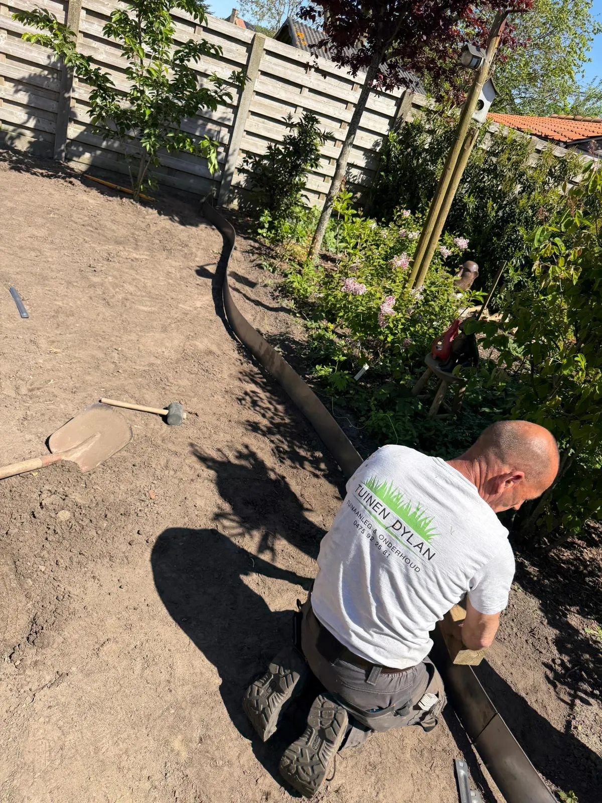 Tuinman van Tuinen Dylan die een borderrand plaatst in de tuin